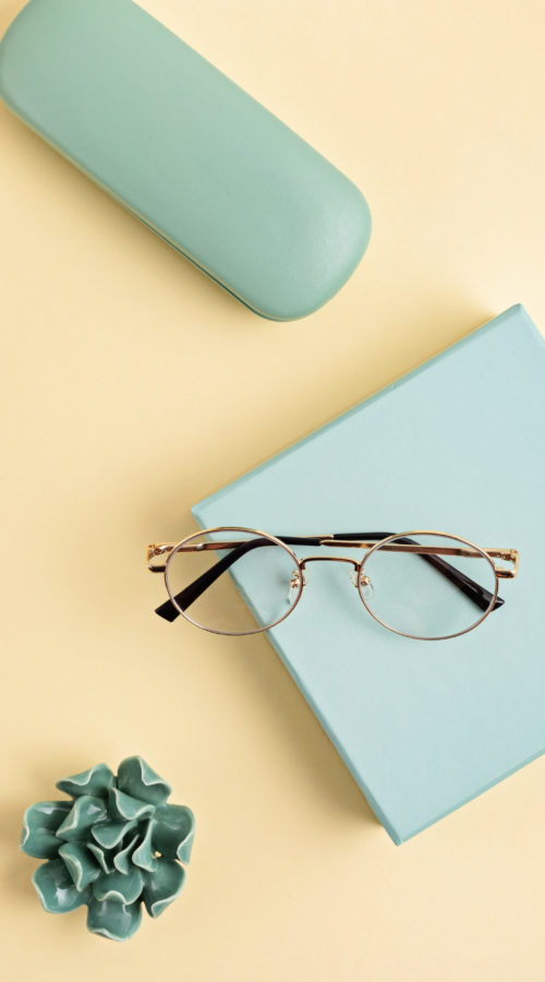 Stylish eyeglasses over pastel  background. Optical store, glasses selection, eye test, vision examination at optician, fashion accessories concept. Top view, flat lay